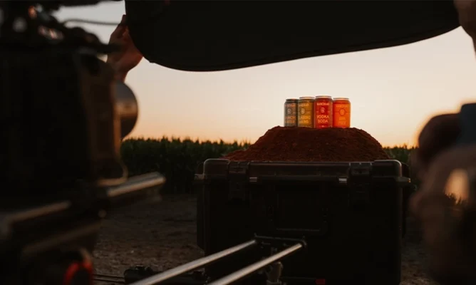 Cans of flavored drinks displayed on a mound of spice during a sunset product photoshoot in an outdoor setting.
