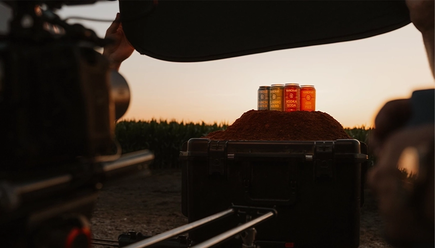 Cans of flavored drinks displayed on a mound of spice during a sunset product photoshoot in an outdoor setting.