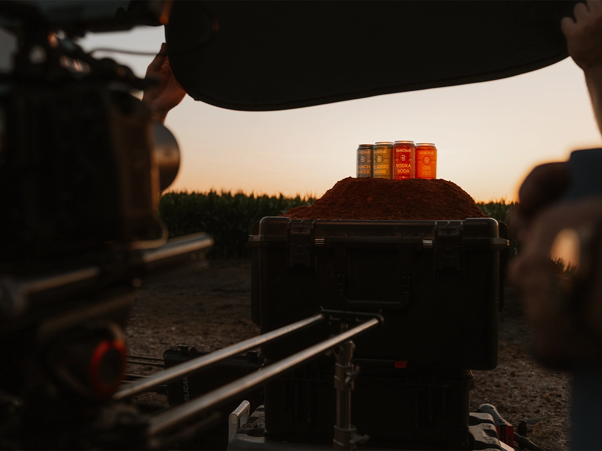 Cans of flavored drinks displayed on a mound of spice during a sunset product photoshoot in an outdoor setting.