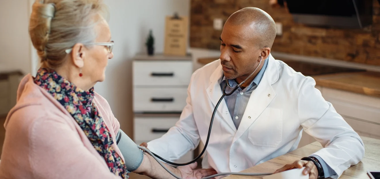 Doctor checking a senior woman’s blood pressure during a home medical consultation.