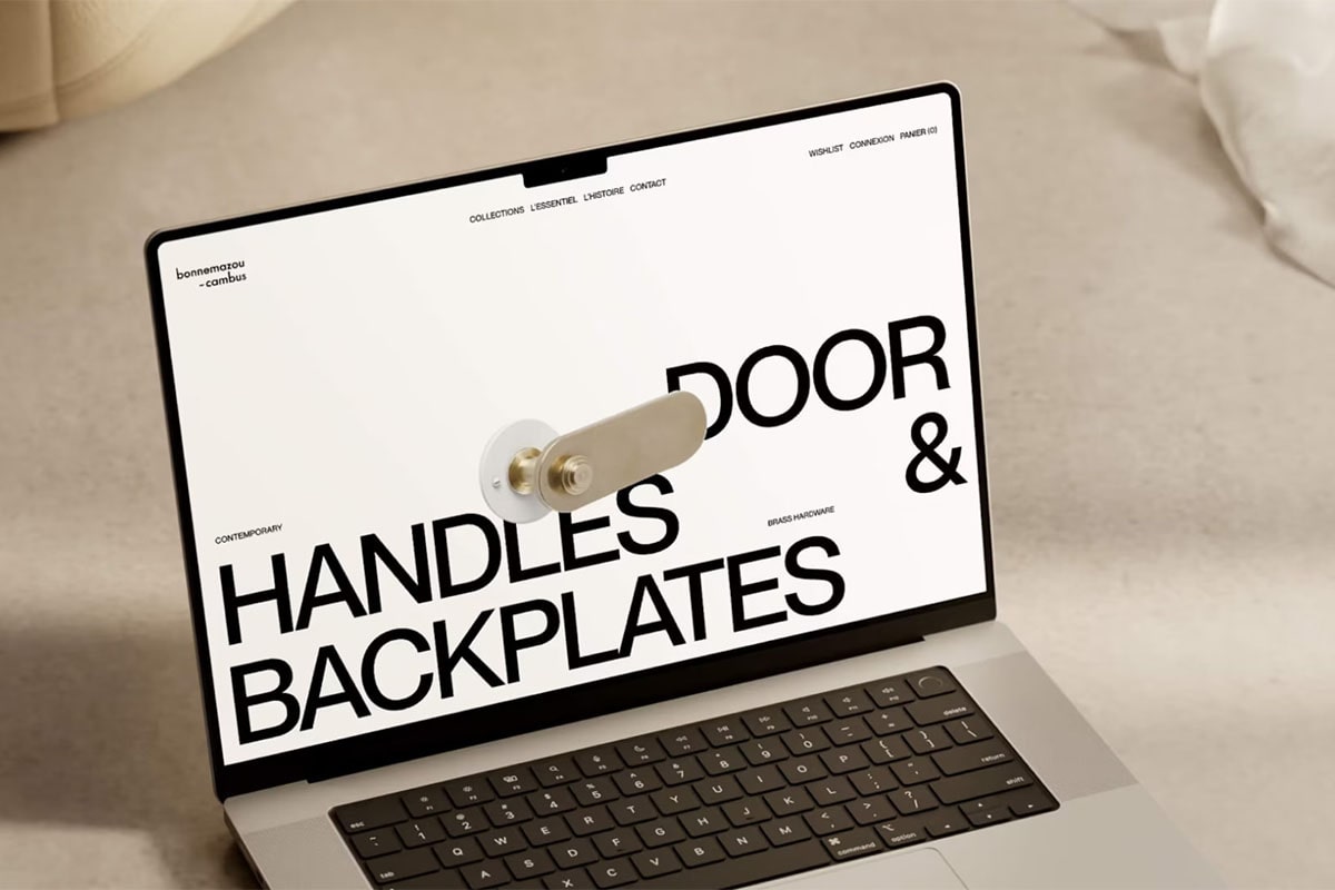 Modern website design displayed on a laptop showcasing contemporary door handles and backplates with bold minimalist typography and brass hardware imagery.