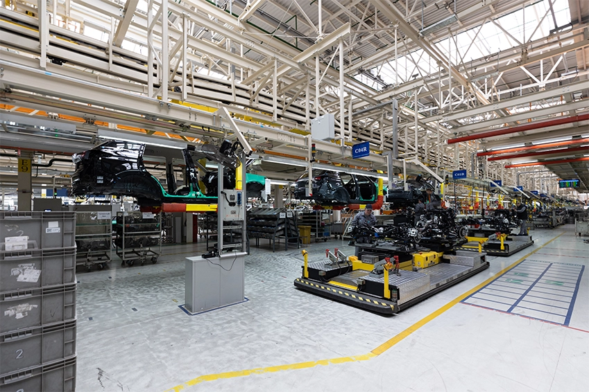 Modern automotive manufacturing plant with vehicle chassis on an assembly line in a high-tech factory setting.