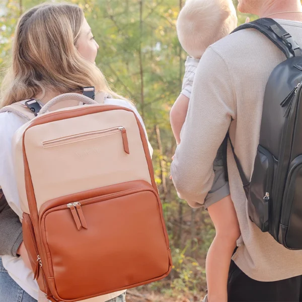 Parents carrying MAPAII diaper backpacks in neutral and black colors while holding their babies outdoors, showcasing stylish, functional, and gender-neutral designs for modern parenting on the go.