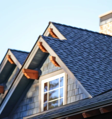 Close-up of an asphalt shingle roof on a modern home with decorative wooden eaves and a brick chimney.