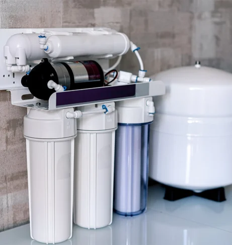 Reverse osmosis water filtration system installed indoors with multiple filter cartridges and pressure tank.